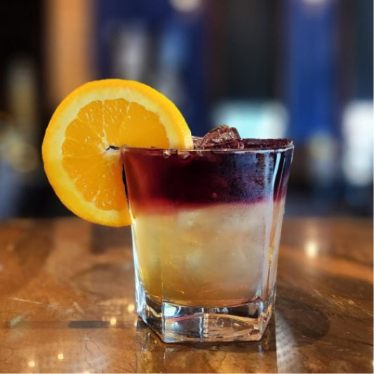 Fresh citrus cocktail with orange slice garnish at Ruth's Chris steakhouse, showcasing premium beverages and inviting bar ambiance.