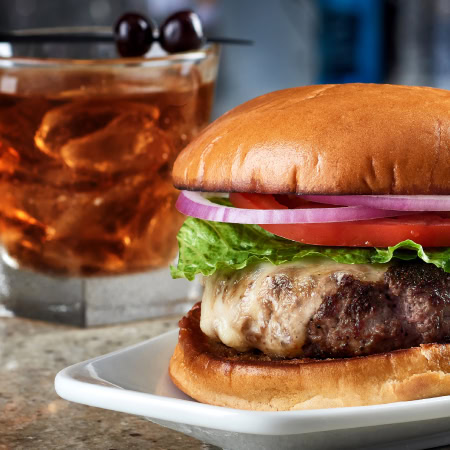 Juicy cheeseburger with fresh lettuce, tomato, onions, and melted cheese served on a toasted bun at Ruth's Chris Steak House.