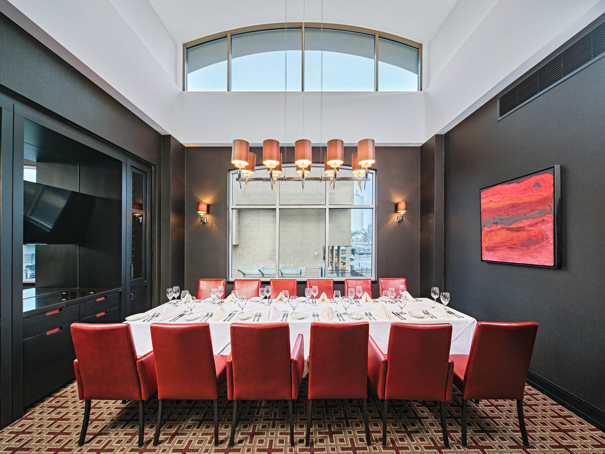 Luxurious Ruth's Chris private dining room with elegant red chairs, modern lighting, and sophisticated decor, perfect for upscale events and gatherings.