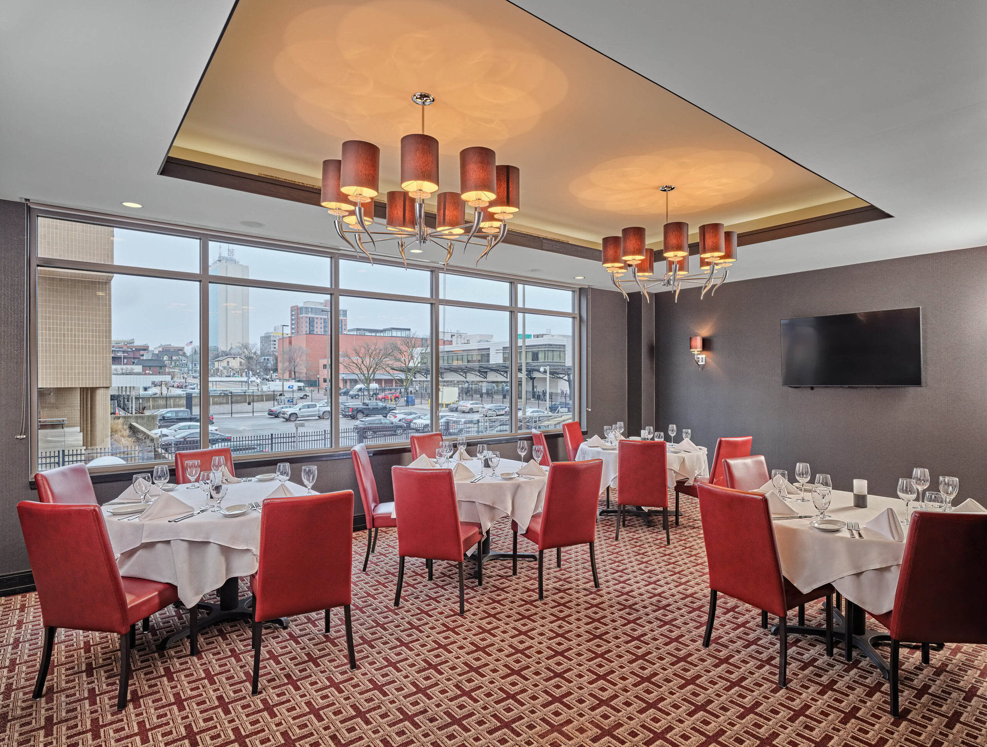 Luxurious restaurant interior at Ruth's Chris steakhouse with elegant red chairs, white tablecloths, and modern lighting, offering a sophisticated dining experience.